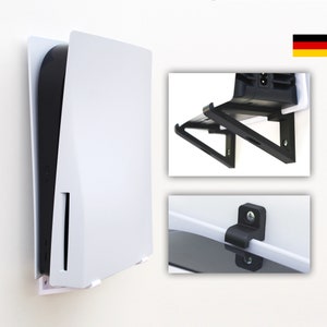 Puede incluir: Soporte de pared blanco para una consola PlayStation 5. El soporte está hecho de plástico blanco y tiene un soporte de plástico negro en la parte inferior. El soporte está diseñado para sostener la consola verticalmente.