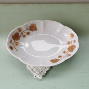 Peut inclure: Plat de service en porcelaine blanche avec un bord festonné et un motif de feuilles d'or.