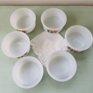 May include: Set of six white ramekins with floral designs. The ramekins are made of glass and have a smooth, white finish. They are perfect for serving desserts, dips, or other small dishes.