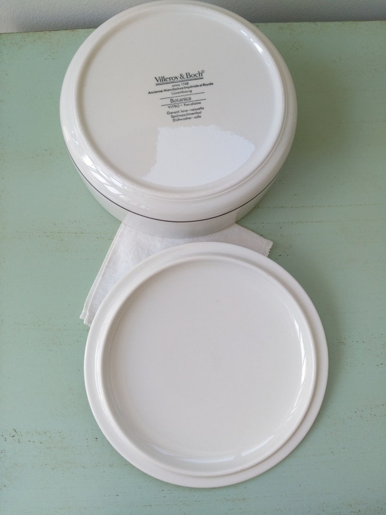 May include: White ceramic lidded storage container with a black and white label that reads "Villeroy & Boch" and "Botanica" on the bottom. The label also includes the text "Germany - Porcelaine" and "Dishwasher safe".