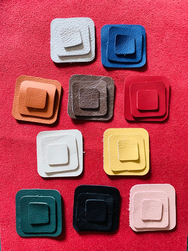 May include: Twelve leather squares in various colors, each with three concentric squares, arranged in three rows of four squares.