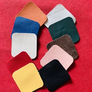 May include: Ten different colored leather squares arranged in a circle on a red background. The colors are: orange, blue, white, green, brown, pink, red, yellow, and black.