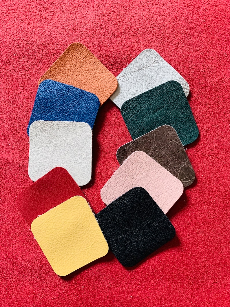 May include: Ten different colored leather squares arranged in a circle on a red background. The colors are: orange, blue, white, green, brown, pink, red, yellow, and black.