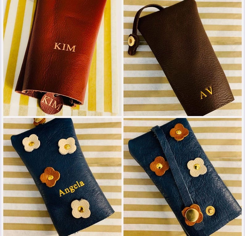 May include: Four leather keychains in various colors: burgundy, brown, and navy blue. The burgundy keychain has "KIM" embossed on it. The brown keychain has "AV" embossed. The navy blue keychains have flower accents and the name "Angela" embossed.