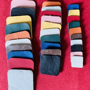 May include: A collection of leather swatches in various colours and textures, including pink, orange, yellow, green, brown, blue, red, and white. The swatches are arranged in two columns, with the left column containing 13 swatches and the right column containing 10 swatches.