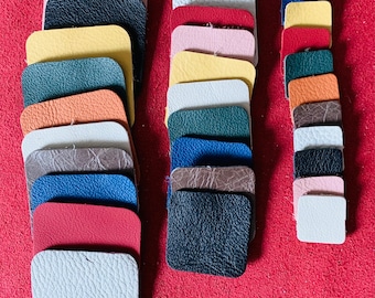 May include: A collection of leather swatches in various colors and textures, including pink, orange, yellow, green, brown, blue, red, and white. The swatches are arranged in two columns, with the left column containing 13 swatches and the right column containing 10 swatches.