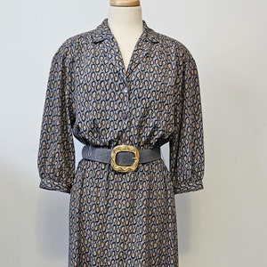 May include: A gray and brown patterned dress with a collared neckline and a button closure. The dress has a belt with a gold buckle.