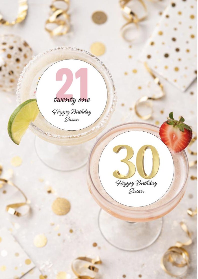 May include: Two cocktails with birthday decorations. One glass has a lime wedge and a circle with the number "21" and the text "twenty one Happy Birthday Susan". The other glass has a strawberry and a circle with the number "30" and the text "Happy Birthday Susan".