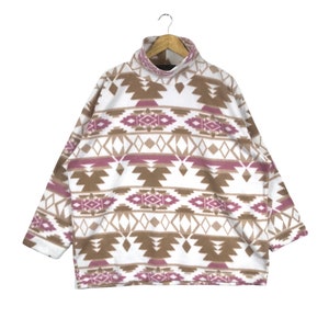 Puede incluir: Sudadera de vell&oacute;n blanca con un patr&oacute;n geom&eacute;trico marr&oacute;n y rosa.