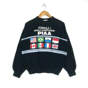 May include: Black sweatshirt with a white graphic of the Formula 1 World Championship logo and the word "PIAAA" with flags of different countries below it.