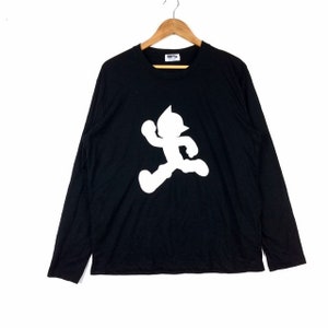 May include: Black long-sleeve t-shirt with a white silhouette of Astro Boy running on the front.