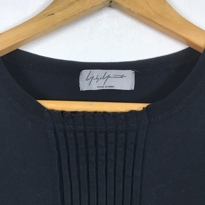 May include: Black t-shirt with a white label that says "Yohji Yamamoto POUR HOMME".