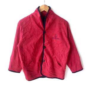 May include: A red fleece jacket with a black trim and a navy blue embroidered logo that says "Gianni Valentino" on the front.