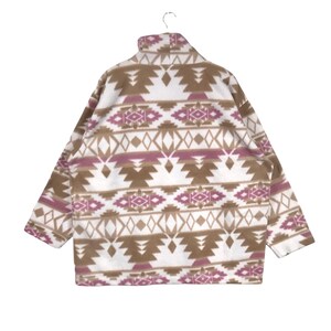 Puede incluir: Una chaqueta de forro polar blanca con un patr&oacute;n geom&eacute;trico marr&oacute;n y rosa. La chaqueta tiene un cuello alto y una cremallera.