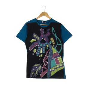 May include: A black t-shirt with a blue trim and a colorful abstract design. The design features a large, multi-colored sun with a geometric pattern and a smaller, multi-colored triangle with a zig-zag pattern.