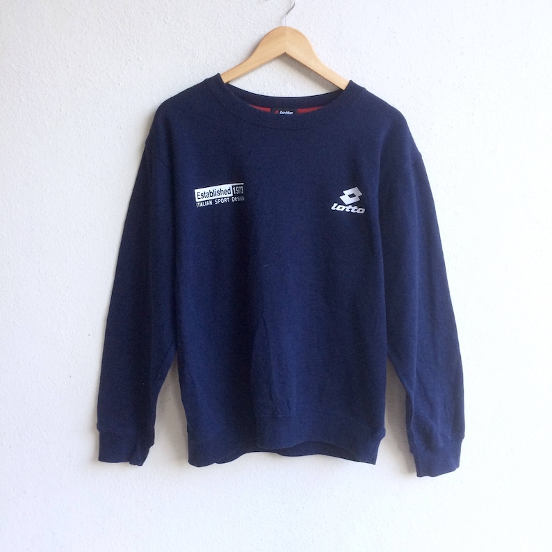 May include: A navy blue sweatshirt with a white Lotto logo and the text "Established 1977 Italian Sport Design" on the front.