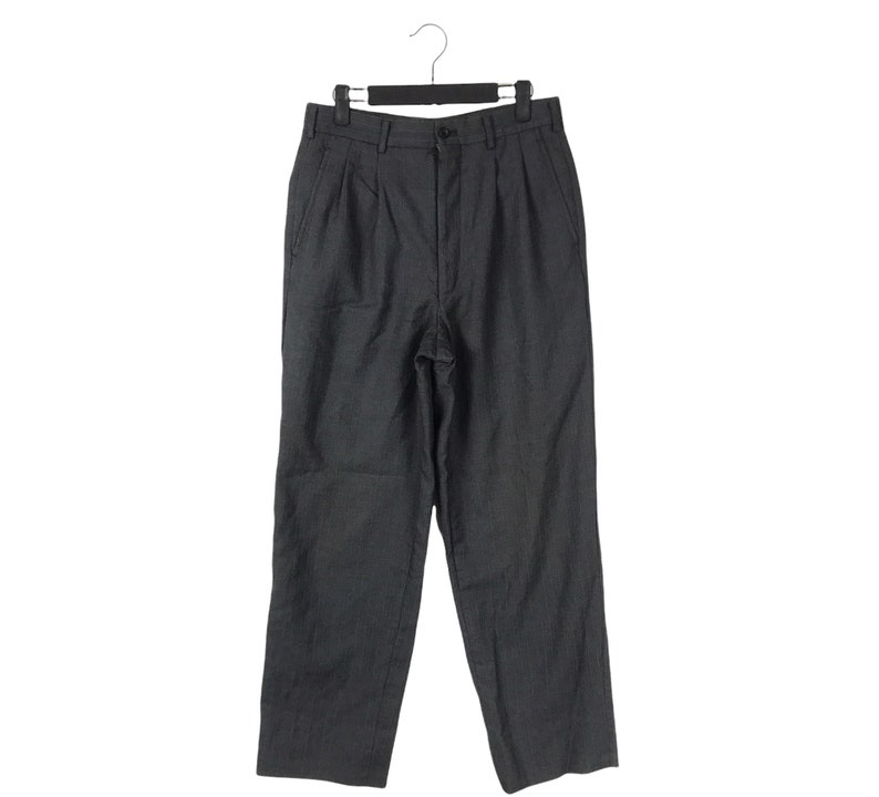 May include: Dark gray trousers with a button closure and pleats. The pants are hanging on a black hanger against a white background. The fabric appears to be a woven material.