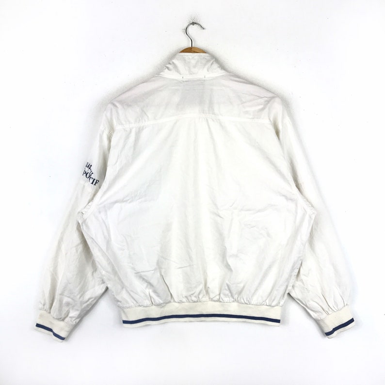 May include: White windbreaker jacket with blue trim and the text "Lacoste Sport" on the sleeve.