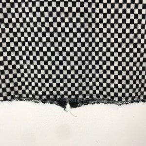 Puede incluir: Tela a cuadros en blanco y negro con un borde deshilachado. La tela tiene una textura de punto.