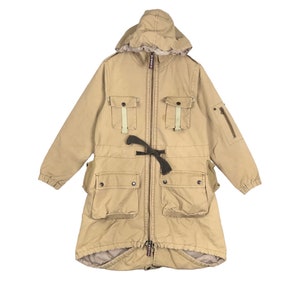 May include: A long, beige, hooded parka with multiple pockets and a drawstring waist. The parka has a zip closure and a flap with buttons.