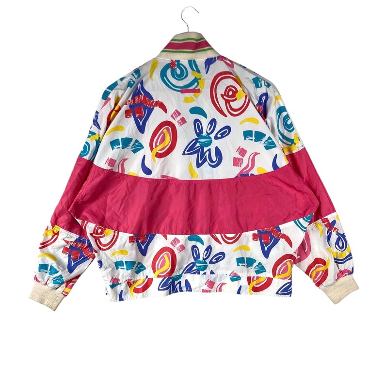 K&ouml;nnte beinhalten: Vintage wei&szlig;e Jacke mit einem lebendigen Muster aus roten, blauen, gelben und t&uuml;rkisfarbenen Formen. Die Jacke hat ein breites pinkfarbenes Band &uuml;ber der Brust und den &Auml;rmeln, mit cremefarbenen B&uuml;ndchen und Kragen.