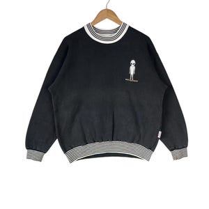 May include: Black sweatshirt with a white and black striped collar and cuffs. The sweatshirt features an alien graphic and the text "Bad Neighbor" in gold lettering.