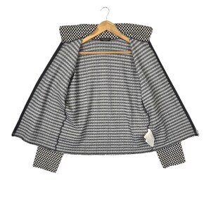 Puede incluir: Chaqueta a rayas blancas y negras con un patr&oacute;n a cuadros en el cuello y los pu&ntilde;os. La chaqueta est&aacute; abierta y el forro es visible.