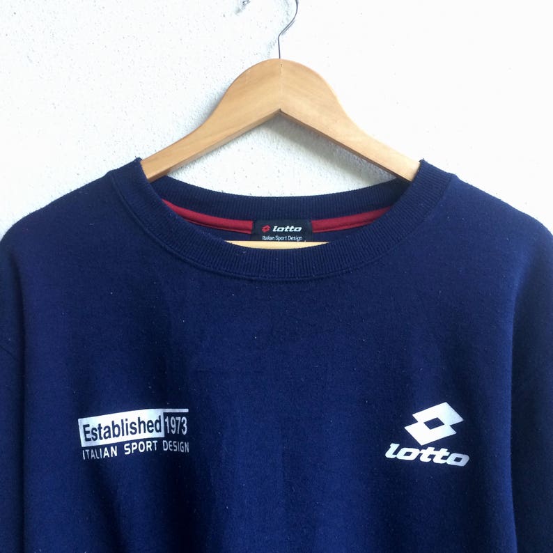 May include: A navy blue sweatshirt with the Lotto logo and the text "Established 1973 Italian Sport Design" on the front.