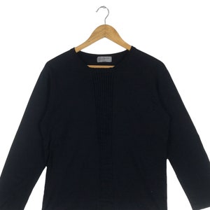 May include: A black long-sleeved shirt with a vertical seam down the front. The shirt has a round neckline.