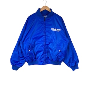 May include: A blue bomber jacket with a white zip and white "Calsonic Racing Team" text on the front.