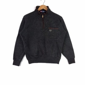 May include: A dark gray quarter-zip sweater with a brown zipper and a brown pocket with a logo on the left chest. The sweater has long sleeves and a ribbed collar.
