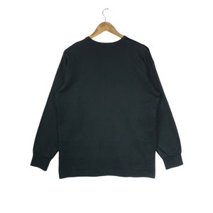 Puede incluir: Una camiseta negra de manga larga con cuello redondo.