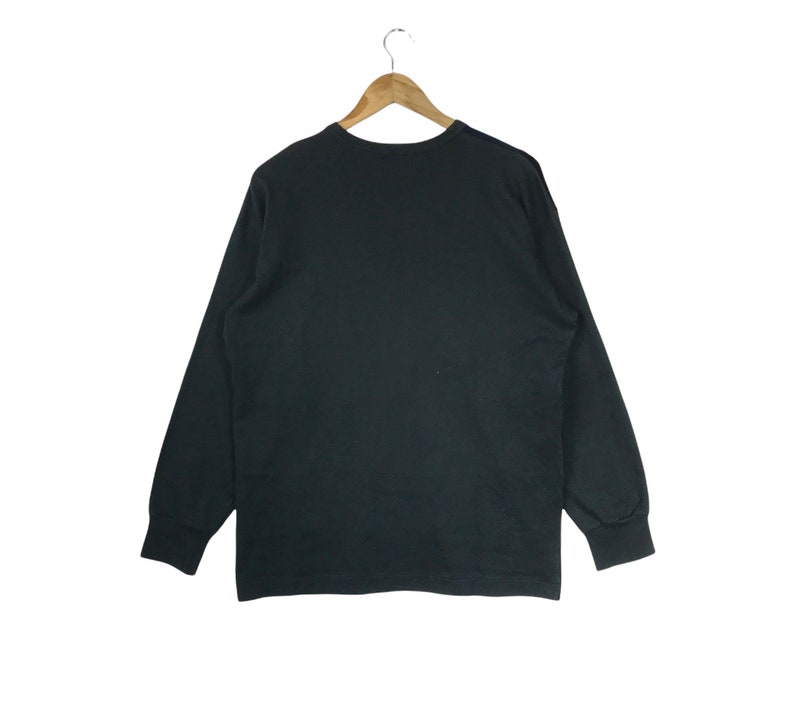 Puede incluir: Una camiseta negra de manga larga con cuello redondo.