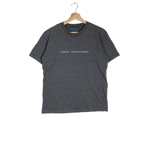 May include: A grey short-sleeved t-shirt with the text "MARITHE + FRANCOIS GIRBAUD" printed on the front.
