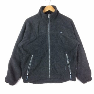 May include: A grey fleece zip-up jacket with a stand-up collar and two zipped pockets on the front. The jacket has a small "J.CREW" logo on the left chest.