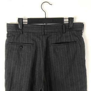 May include: Grey pinstripe dress trousers with a button fly and two back pockets.