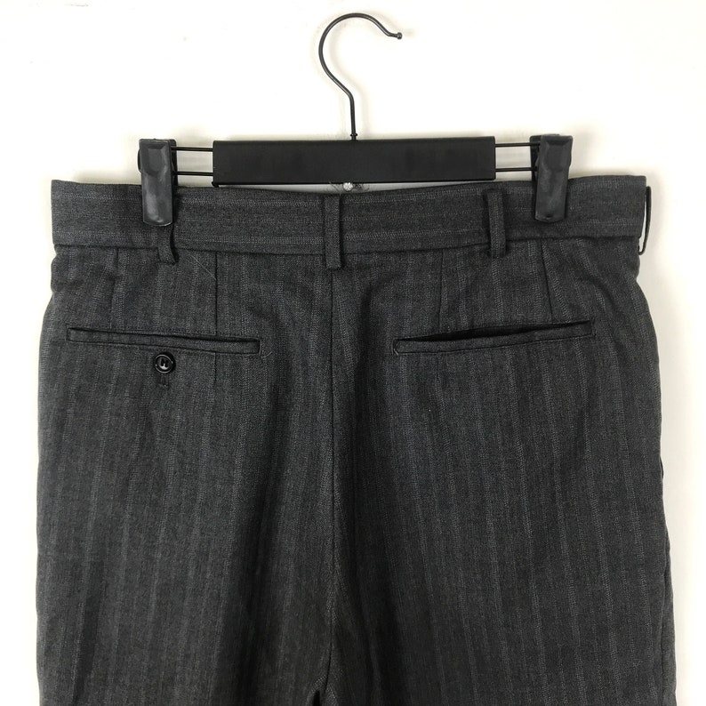 May include: Grey pinstripe dress trousers with a button fly and two back pockets.