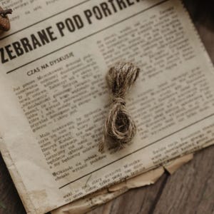 May include: A close-up of a newspaper with the headline "Zebrane Pod Portrew" and the text "Czas na dyskusje" in Polish. A small piece of twine is on top of the newspaper.