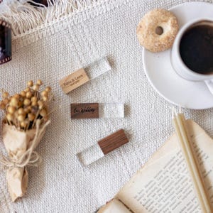 Può includere: Tre chiavette USB rettangolari composte da un blocco di legno naturale e uno di acrilico trasparente. Una unità è incisa con il testo Fabio & Laura 14.07.2023, un'altra con Our Wedding, e la terza è vuota con una finitura in legno scuro.
