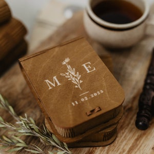 May include: A wooden box with a floral design and the initials "M & E" engraved on the top. The box is closed and has a date, "11.02.2023", engraved on the front. The box is sitting on a wooden surface.