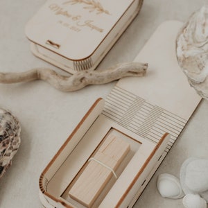 May include: A wooden box with a lid that opens to reveal a wooden USB drive. The box is engraved with the text "Matthew & Jessica" and the date "18.12.2021".