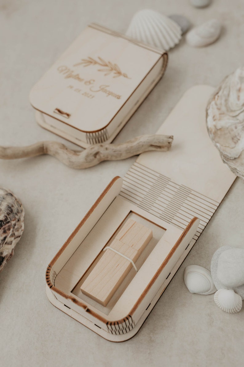 May include: A wooden box with a lid that opens to reveal a wooden USB drive. The box is engraved with the text "Matthew & Jessica" and the date "18.12.2021".