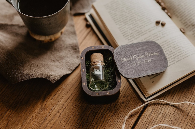 May include: A small wooden box with a glass vial containing a USB drive. The box is engraved with the text "Alan & Cynthia Mackey 4.30.2019".