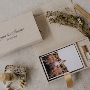 May include: A beige linen box with a photo print and a USB drive inside. The box is personalized with the text "Laura & Antoine 22.07.2023".