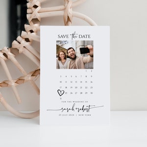 May include: Save the date card with a calendar featuring a heart on July 25th. The card has a photo of a couple taking a selfie and the text "SAVE The DATE" and "FOR THE WEDDING OF sarah+robert 25 JULY 2024 | NEW YORK".