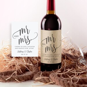 May include: A brown paper wine bottle label with the text "Mr. and Mrs." in a cursive font. The label also includes the text "Cheers to love, laughter and happily ever after!" and the names "Stephany & Clayton" with the date "08.07.22".