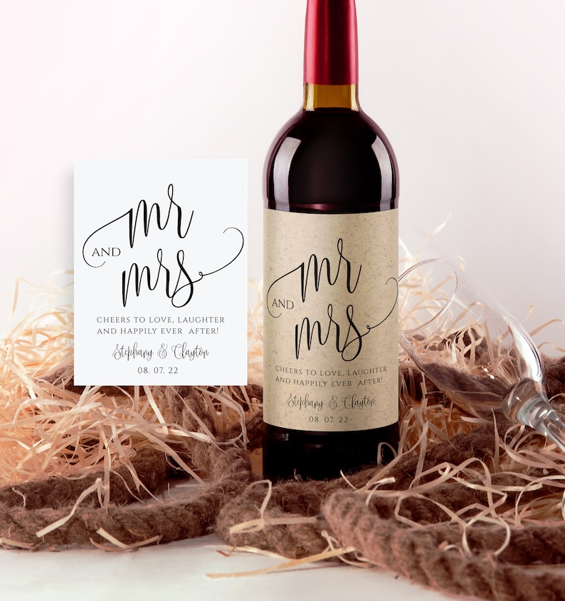 May include: A brown paper wine bottle label with the text "Mr. and Mrs." in a cursive font. The label also includes the text "Cheers to love, laughter and happily ever after!" and the names "Stephany & Clayton" with the date "08.07.22".