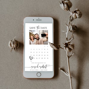 May include: A digital save the date card with a photo of a couple taking a selfie. The card features a calendar with the date circled in red and the text "SAVE The DATE" at the top. The text "FOR THE WEDDING OF sarah + robert" is below the calendar, along with the date "25 JULY 2024" and the location "NEW YORK".