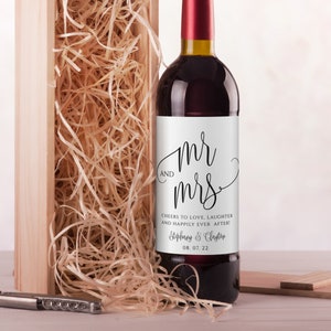 May include: A white wine bottle label with black calligraphy that reads "mr & mrs" and the text "Cheers to love, laughter and happily ever after!"  The label also includes the names "Stephany & Clayton" and the date "08. 07. 22".
