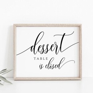 May include: A white sign with a black frame and the text "dessert table is closed" in a cursive font.